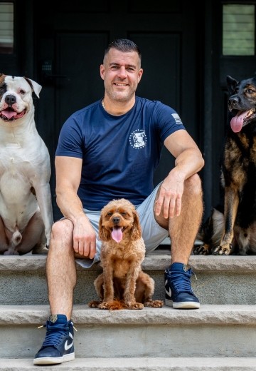 Steve Del Savio seated on the lodge steps with three dogs at his side