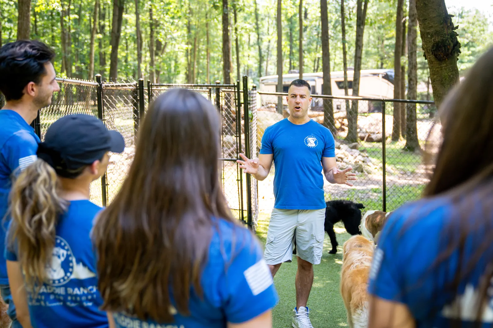 Steve Del Savio teaching a group on the turf yard, the team listening in the foreground.